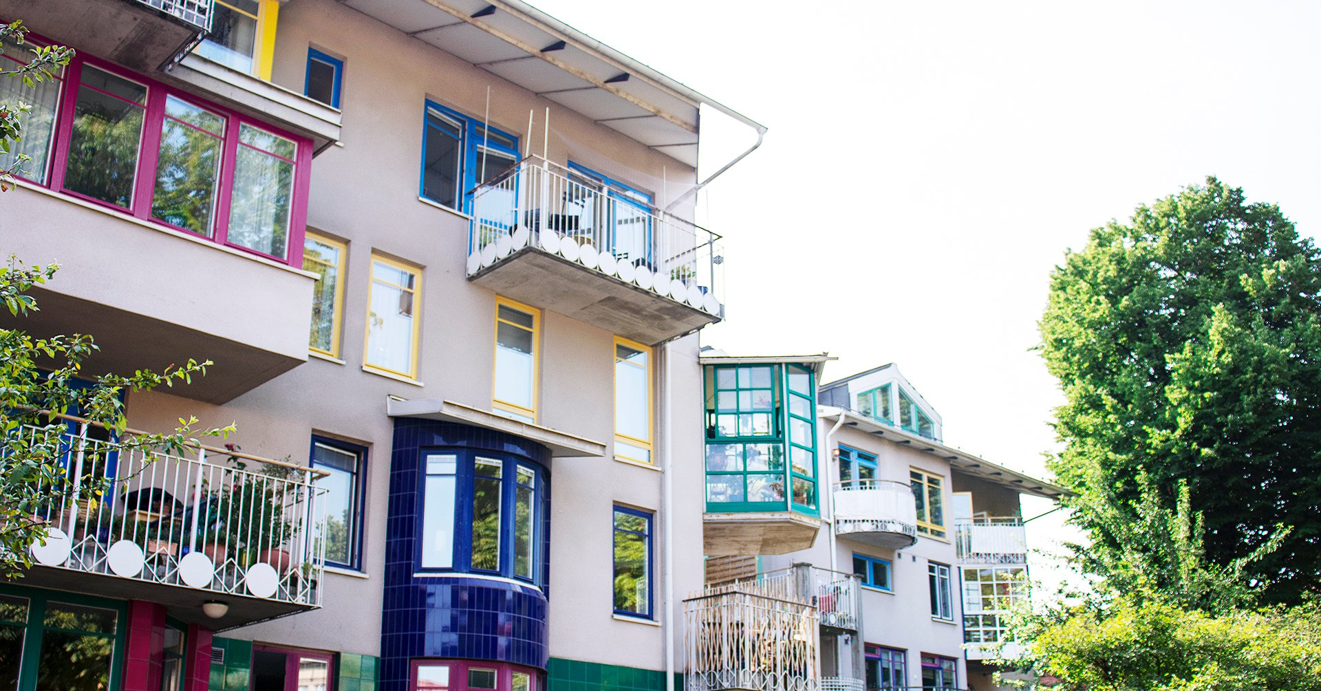 På bilden syns en bostadsrättsförenings fasad. Fasaden har många balkonger i olika färger och former.