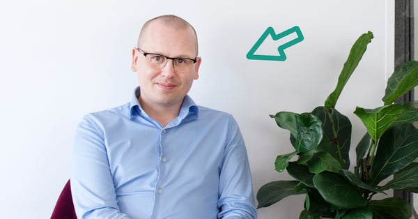 På bilden syns karl Emil Nikka sittandes i en röd fåtölj. Han har en ljusblåskjorta och glasögon på sig.