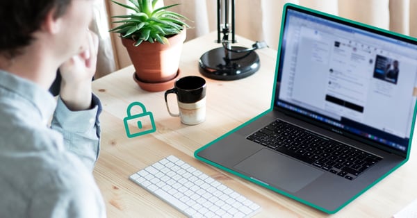 På bilden syns en person i förgrunden som sitter framför en laptop och funderar på begreppet IT-säkerhet.