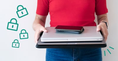 På bilden syns en person i röd tröja med blå jeans som håller i en laptop på vilken det ligger en grå surfplatta och en svart smartphone.