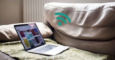 På bilden syns en öppen laptop som ligger på en ljusgrön soffa. Jämte soffan syns en WiFi-symbol i grönt.